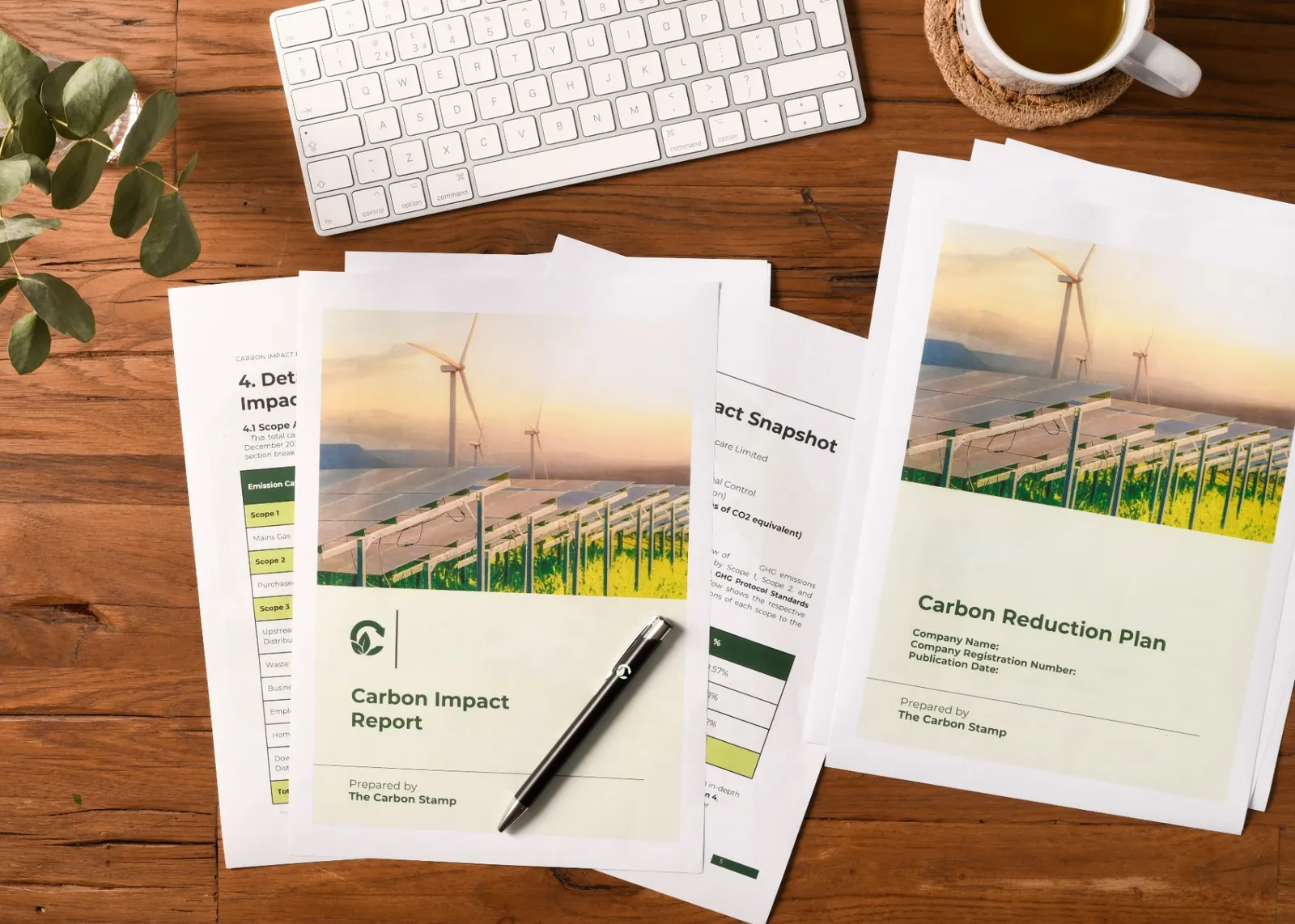 The Carbon Stamp carbon impact reports and carbon reduction plans on a wooden desk with keyboard and coffee